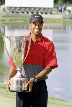 a man holding a trophy in front of a lake