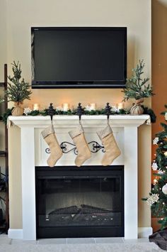 a fireplace with stockings hanging from the mantel and christmas decorations on it, along with a flat screen tv above