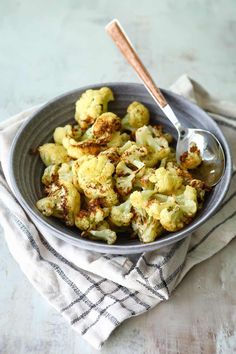 a bowl filled with cooked cauliflower on top of a white and black towel