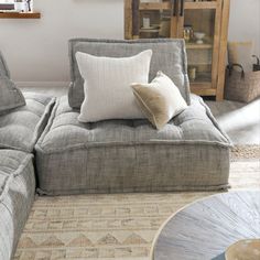 a living room with a gray couch and pillows on top of the couch is next to a coffee table