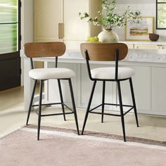 two stools in front of a kitchen counter with flowers on the table and an area rug