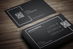 two black business cards with qr code on them, sitting on a wooden table