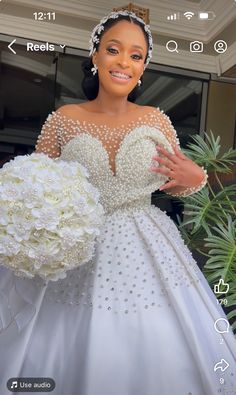 a woman in a white wedding dress holding a bouquet and wearing a tiara with pearls on it