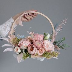 a person holding a basket with flowers in it