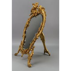 an ornately decorated gold framed mirror sitting on top of a table