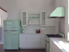 a green refrigerator freezer sitting inside of a kitchen next to a stove top oven