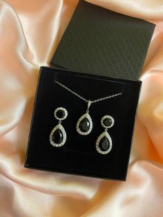 Luxury top quality black cubic zirconia earrings and necklace bridal set includes : # Earrings featuring a large teardrop with pear cut black cubic zirconia center surrounded by tiny round zirconia crystals. Teardrop dangles from a ear stud with brilliant cut black cubic zirconia center and surrounded by tiny round zirconia crystals.   This entire halo setting gives a brilliantly beautiful effect.  Total length of the earrings is 3.5 cms. #Necklace pendant featuring a large teardrop with pear cut black cubic zirconia center surrounded by tiny round zirconia crystals and dangles from cubic zirconia bail. Length of the rhodium plated chain is 18 inches and comes with 2 inches extender and lobster clasp.    Set includes earrings and necklace, bracelet has to ordered separately. For matching b Formal Teardrop Pendant Jewelry Sets With Cubic Zirconia, Black Cubic Zirconia Necklace For Wedding, Elegant Black Jewelry Sets As A Gift, Hand Set Black Jewelry For Wedding, Black Hand Set Jewelry For Wedding, Elegant Black Jewelry Set For Wedding, Black Crystal Jewelry For Anniversary, Black Teardrop Pendant Jewelry For Formal Occasion, Elegant Crystal Jewelry With Black Diamonds