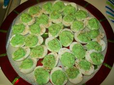 deviled eggs with green frosting and sprinkles on a red plate