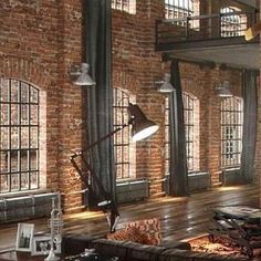 a large living room with exposed brick walls and floor to ceiling windows on the second floor