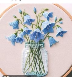 blue flowers are in a mason jar on a white background with the words stitching