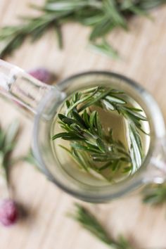 a cup filled with water and herbs on top of a wooden table