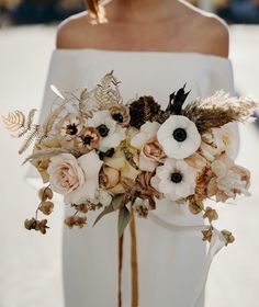 a bridal bouquet with white and brown flowers on the bride's waistline