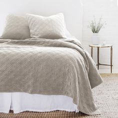 a bed with two pillows on top of it and a white brick wall in the background