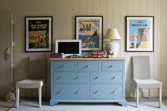 a blue dresser sitting next to a white chair in a room with pictures on the wall