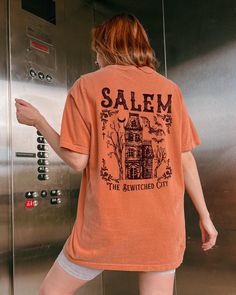 Comfort Colors® Salem Massachusetts shirt, Salem Witchy Haunted House shirt for her, Witch Tshirt, Halloween Party T-shirt Vintage Fall Tee These are Unisex Garment-Dyed T-shirt made 100% with ring-spun cotton. Shirts look retro and vintage. The soft-washed, garment-dyed fabric brings extra coziness to your wardrobe while the relaxed fit makes it an excellent daily choice. FEATURES - Medium fabric (6.1 oz/yd² (206.8 g/m - Relaxed fit - Sewn-in twill label - 100% ring-spun cotton - Without side seams - Garment-dyed fabric - Double needle stitching on all seams Sizing * Please refer to the size chart in the listing photographs to determine your size. * If you are not sure what size to order, you can measure a shirt you already own to see what size would fit you best. Our shirts are measured Spooky Crew Neck Fitted T-shirt, Spooky Fitted Crew Neck T-shirt, Spooky Orange Crew Neck Top, Spooky Short Sleeve Top With Screen Print, Spooky Crew Neck Shirt With Letter Print, Spooky Short Sleeve Shirt With Letter Print, Fitted Halloween T-shirt With Crew Neck, Fitted Crew Neck Halloween T-shirt, Fitted Cotton Spooky T-shirt