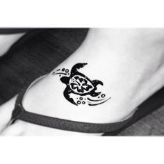 a small turtle tattoo on the side of a woman's foot, which is black and white