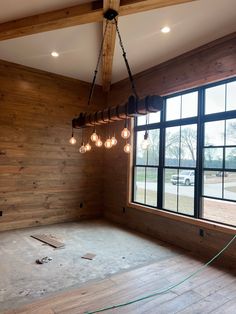 an empty room with wood paneling and light bulbs hanging from the ceiling in front of large windows