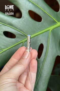 Hand holding small silver tube with blue flash opal dome at bottom, small stones are set in the tube and various holes have been made in the tube, on a silver chain, with large green leaf in the background. Galaxy Necklace, Silver Jewelry Handmade, Sapphire Necklace, Welo Opal, Yellow Sapphire, Chain Lengths, Sterling Silver Chains, Handmade Silver, Blue Yellow