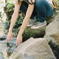 a woman crouches down to look at the water