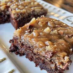 two pieces of chocolate cake with caramel drizzled on them sitting on a white plate