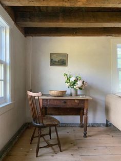 an old desk and chair in a room with white walls, wood floors and exposed beams