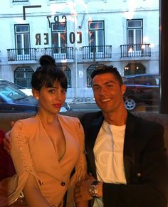 a man and woman posing for a photo in front of a window