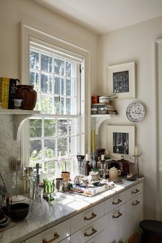 a kitchen counter topped with lots of clutter next to a window covered in windowsills