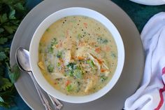 a bowl of soup with broccoli, carrots and chicken on a plate