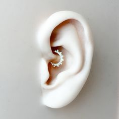 an ear is shown with two small white beads in the middle and one smaller bead at the end