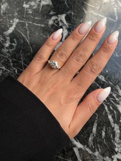 a woman's hand with white manies and a diamond ring on top of it