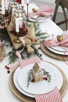 the table is set for christmas with plates and napkins on it, candlesticks in