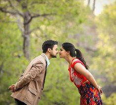 a man and woman kissing each other in front of trees