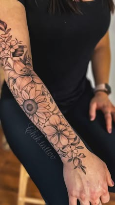 a woman's arm with sunflowers and leaves tattoo on her left arm