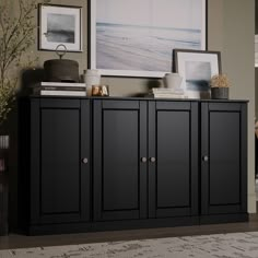 a black cabinet in a living room with pictures on the wall above it and an area rug