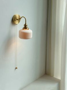 a wall light that is on the side of a white wall next to a window