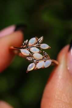 a close up of a person's hand holding a ring with opals on it