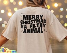 a woman wearing a merry christmas ya filthy animal t - shirt in front of lights