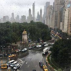 a city street filled with lots of traffic next to tall buildings in the rain covered sky