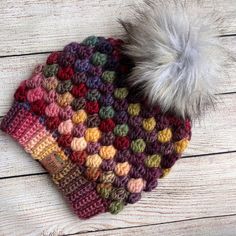 a multicolored knitted hat with a fur pom