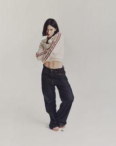 a young woman is posing in jeans and a white shirt with her hands on her hips