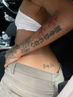 a woman with tattoos on her stomach in the back seat of a car while holding onto another person's arm