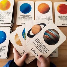 a person holding up six cards with different planets on them