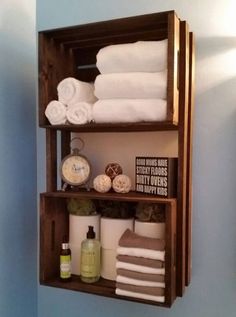 a bathroom with blue walls and white towels on the shelf above the toilet is an open shelving unit