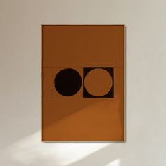 an orange and black square with two circles on the opposite side, in front of a white wall