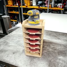 a sanding machine sitting on top of a wooden box filled with red discs in a shop