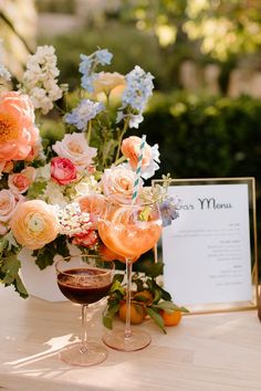 two glasses of wine on a table with flowers and an menu in the back ground