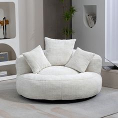 a living room with a round chair and white pillows on the floor, along with bookshelves