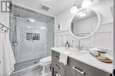 a bathroom with white tile and gray vanity, mirror, toilet, shower stall and sink