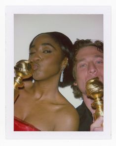 a man and woman holding golden objects in their mouths while standing next to each other