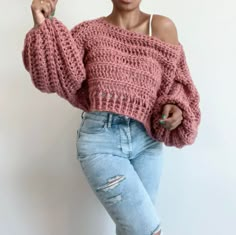 a woman in ripped jeans and a pink sweater posing for the camera with her hand on her hip